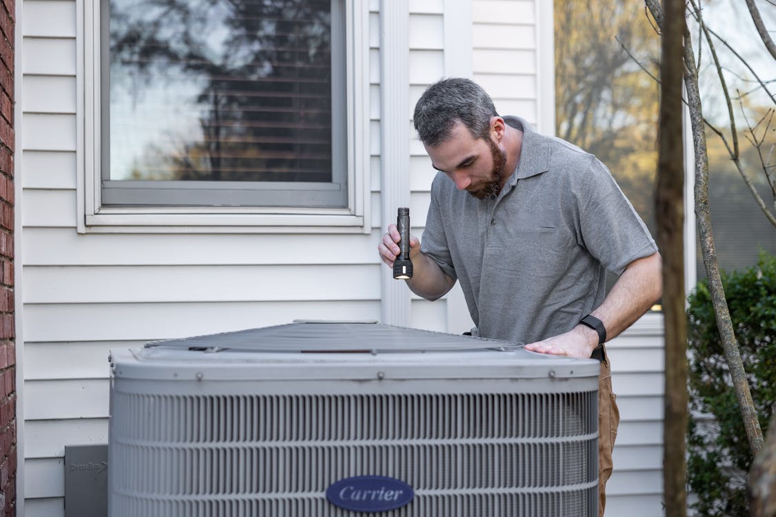 Technician inspecting an outdoor AC unit