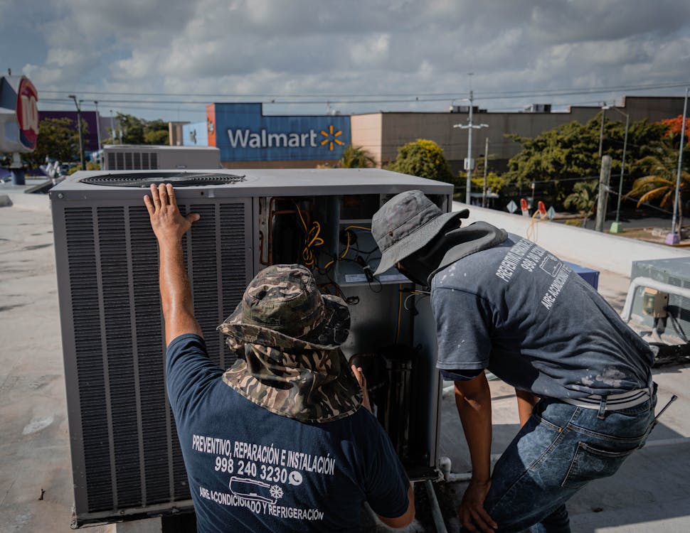 Two HVAC technicians inspecting an outdoor air conditioning unit